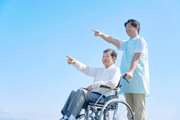 介護士と車椅子に乗る高齢者　屋外