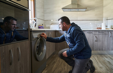 Middle-aged man putting clothes in the washing machine