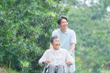 介護士と車椅子に乗る高齢者　屋外