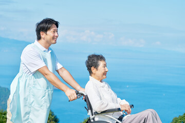 介護士と車椅子に乗る高齢者　屋外