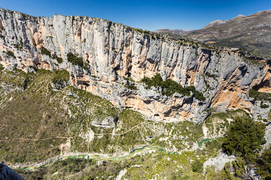 Falaise calcaire verticale formant un canyon avec un sentier et une rivi&egrave;re &eacute;meraude dans le fond. Site d'escalade, Barres de l'Escal&egrave;s et sentier Blanc-Martel, Gorges du Verdon, France