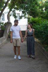 Positive happy young heterosexual couple in love walking in the park in summer hiking relationship