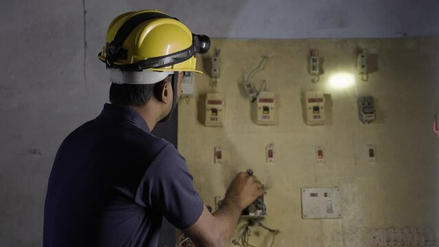 electrician busy checking or repairing electic circuit board during night - concept of repair or maintenance service, safety and skilled blue collar jobs