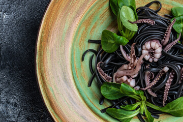 Squid ink spaghetti with seafood octopus, mussels and shrimps on dark background. Restaurant menu,...