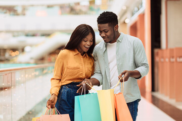 Happy black couple holding shopping bags looking inside