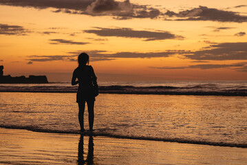 Fototapeta premium Woman walking on the beach at a beautiful sunset in Costa Rica