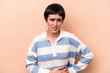 Young caucasian woman isolated on beige background having a liver pain, stomach ache.