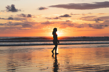 Fototapeta na wymiar Woman walking on the beach at a beautiful sunset in Costa Rica
