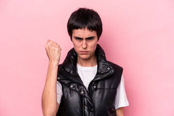 Obraz premium Young caucasian woman isolated on pink background showing fist to camera, aggressive facial expression.