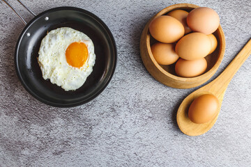 Fried eggs in a pan and fresh eggs on the table