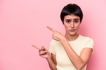 Young caucasian woman isolated on pink background shocked pointing with index fingers to a copy space.