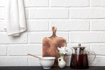 Kitchen background with copy space, white rustic brick wall in loft style. Teapot and honey on the table. Morning tea