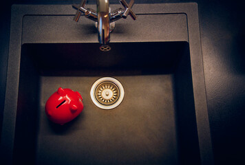 Red piggy bank, money, dark gray shell, silver modern faucet in the background