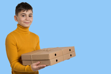 a boy in a yellow sweater, smiling, holds two pizza boxes, food delivery, on a light blue background