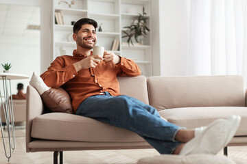 Man having rest at home on the couch, drinking coffee