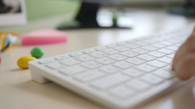 Female hands typing on a white keyboard in office. Close-up of a woman hands on blurred background
