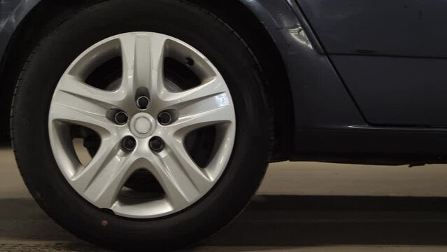 Close up of car driving by at parking lot. Close up of car wheels. No logo on rims