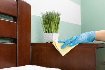 A housewife cleaning the house, wipes dust from the table with a cleaning rag