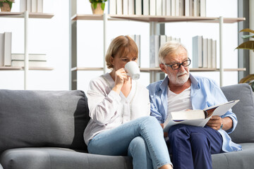 senior couple reading a book and self learning in living room