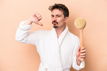 Young caucasian man holding back scratcher isolated on beige background feels proud and self confident, example to follow.