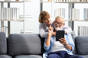 senior couple, elderly man and woman using tablet on sofa