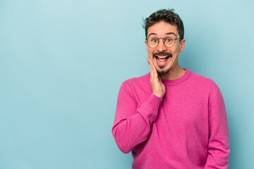 Young caucasian man isolated on blue background shouts loud, keeps eyes opened and hands tense.