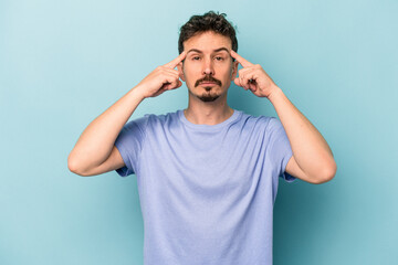Fototapeta na wymiar Young caucasian man isolated on blue background focused on a task, keeping forefingers pointing head.