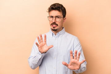 Young caucasian man isolated on beige background rejecting someone showing a gesture of disgust.