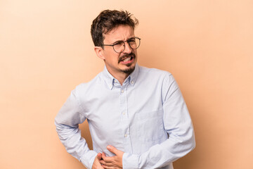 Young caucasian man isolated on beige background having a liver pain, stomach ache.