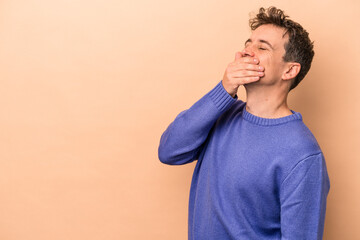 Young caucasian man isolated on beige background laughing happy, carefree, natural emotion.