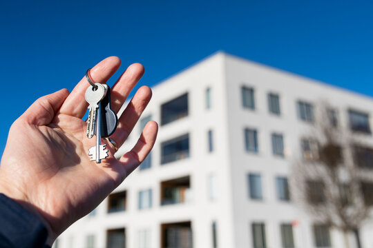 Hand holding keys in front of building