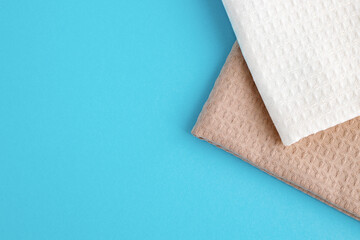 Folded white and beige kitchen towels on a blue background. The concept of natural eco-friendly...