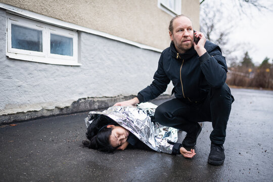 Man calling for ambulance for unconscious woman in medical shock