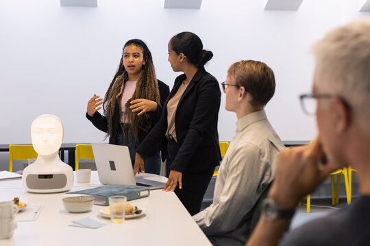 Business people discussing robot voice assistant during meeting