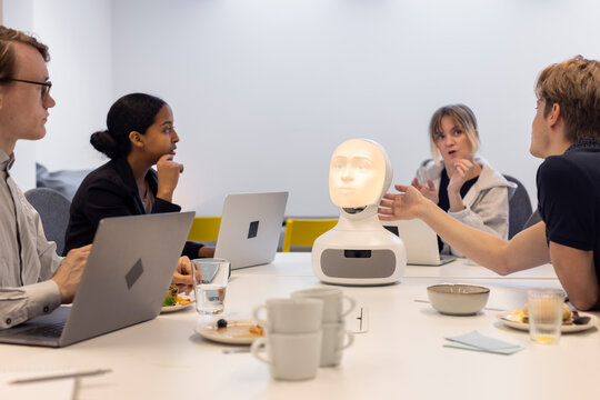 Business people discussing robot voice assistant during meeting
