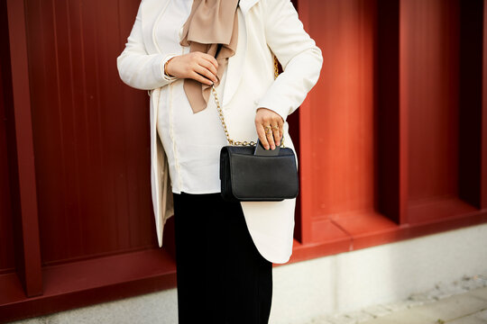 Mid section of woman putting cell phone in bag