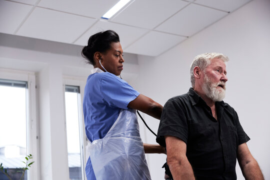 Female doctor examining senior patient with stethoscope