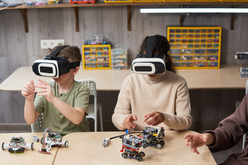Portrait of two children wearing VR gear while building robots in engineering class at school