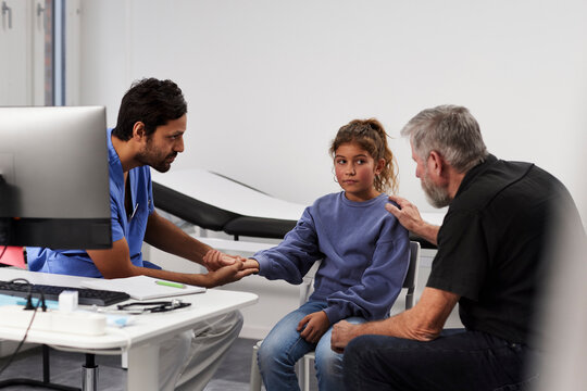 Male doctor examining girl patient's wrist during appointment