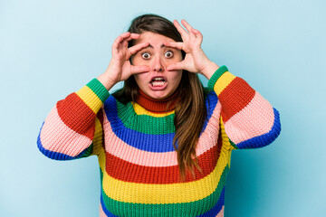 Young caucasian overweight woman isolated on blue background keeping eyes opened to find a success opportunity.