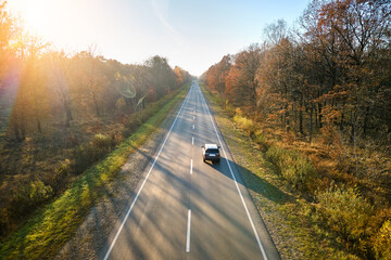 Aerial view of intercity road with blurred fast driving car at sunset. Top view from drone of highway traffic in evening