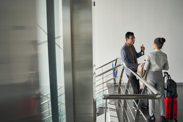 Fototapeta premium Male with travel documents talking to female in corridor