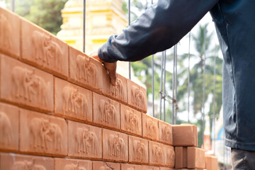 Builder carefully puts red brick on the masonry. Quick work bricklayer. Guy measures level masonry. Man is building brick wall. Correctly calculate material. Builder manually carries brick structure