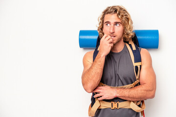 Young mountaineer caucasian man with a big backpack isolated on white background relaxed thinking about something looking at a copy space.