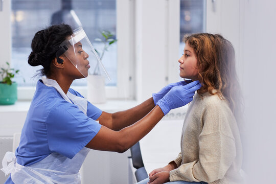 Female doctor examining girl patient's neck