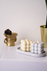 a grey and off-white bubble candles burning on a concrete tray on white sideboard, sansevieria green house plans, smudge stick
