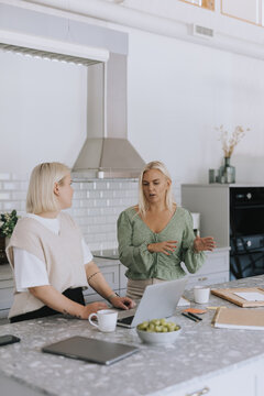 Women using laptop in kitchen