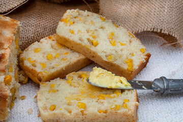 Mielie bread, a South African bread with whole sweetcorn on rustic  kitchen table. sliced with fresh butter melting in