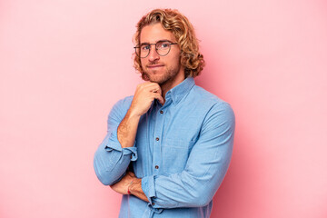 Fototapeta na wymiar Young caucasian man isolated on pink background smiling happy and confident, touching chin with hand.