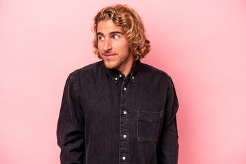 Young caucasian man isolated on pink background laughs and closes eyes, feels relaxed and happy.